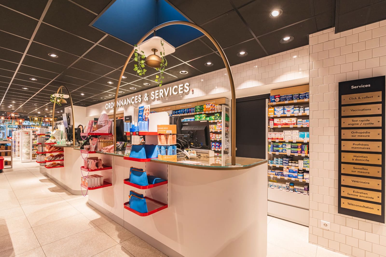 Comptoir Ordonnances & Services : arches de laiton au-dessus des postes, présentoirs rouges et panneau des services
