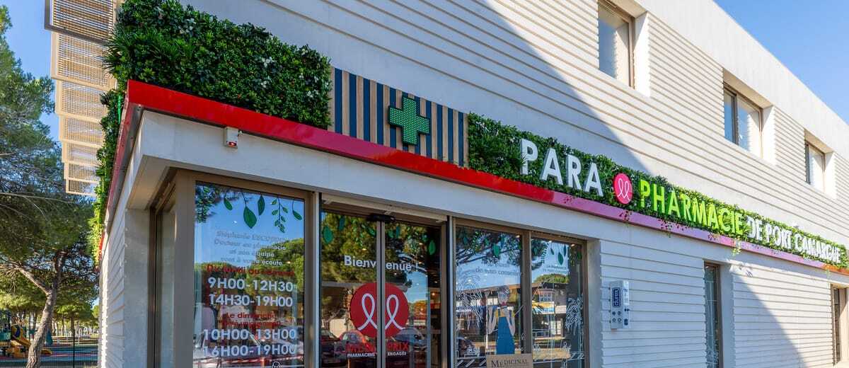 Enseigne végétalisée de la pharmacie de Port Camargue : mur planté, bandeau rouge et lettrage blanc