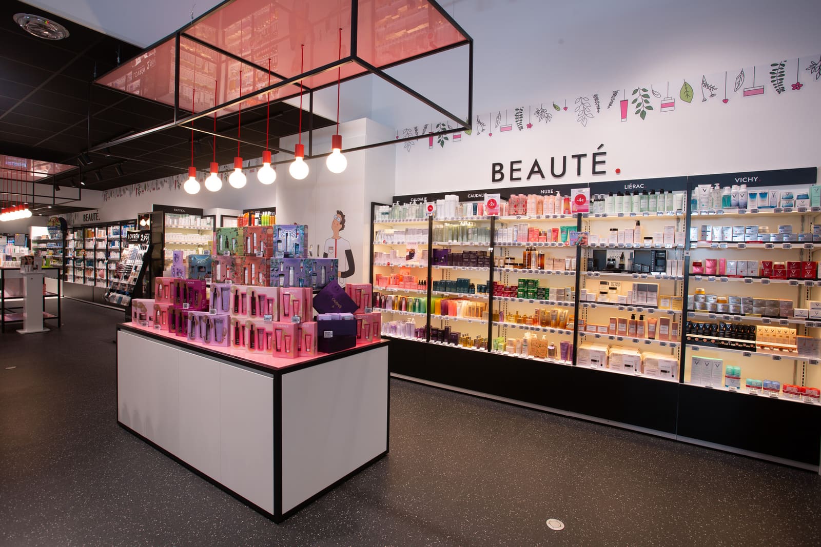 Le podium beauté : îlot au plateau lumineux rose devant le mur de marques signé Beauté